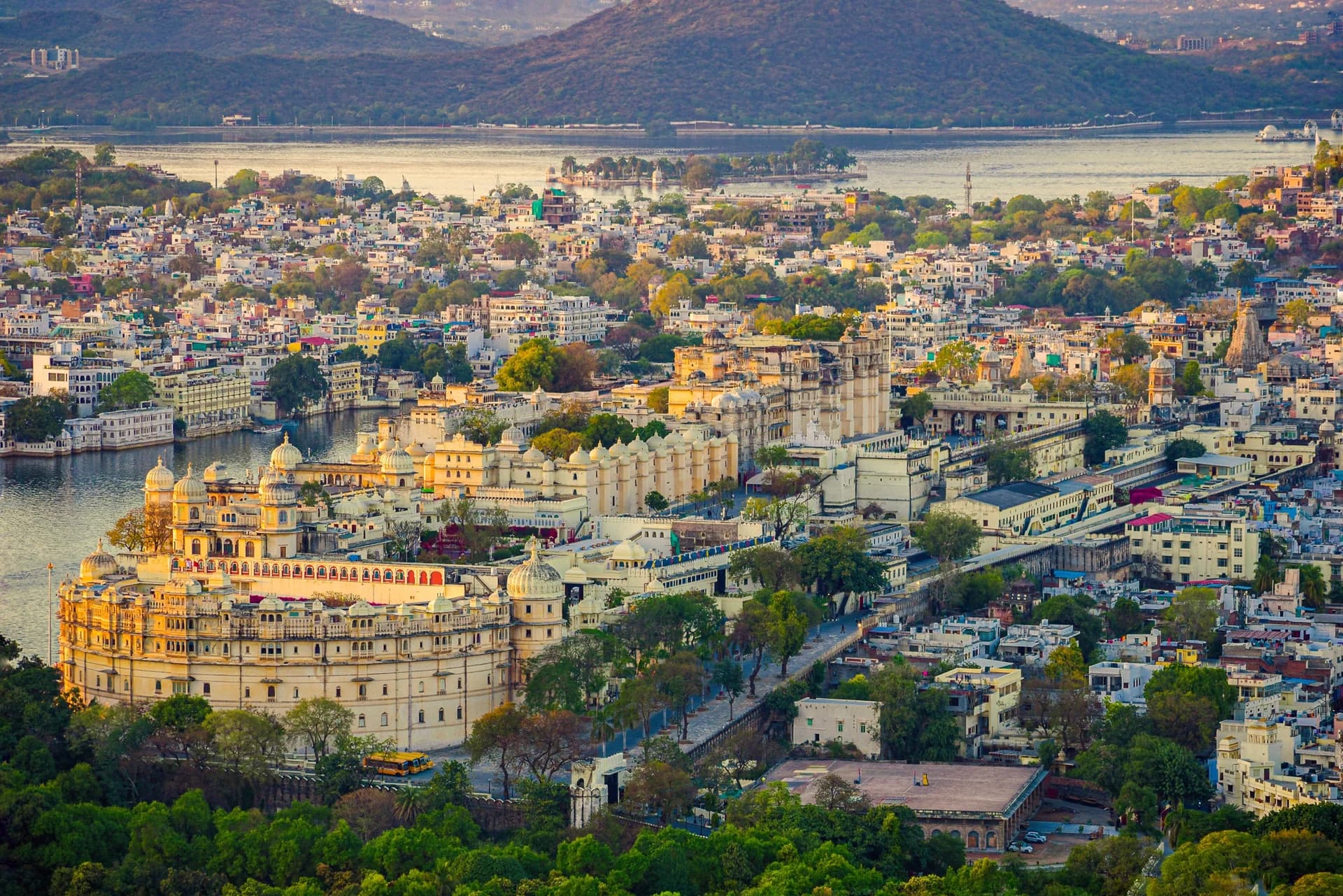 Aerial view of Udaipur's old city at golden hour with the City Palace, Lake Pichola and the Aravalli hills