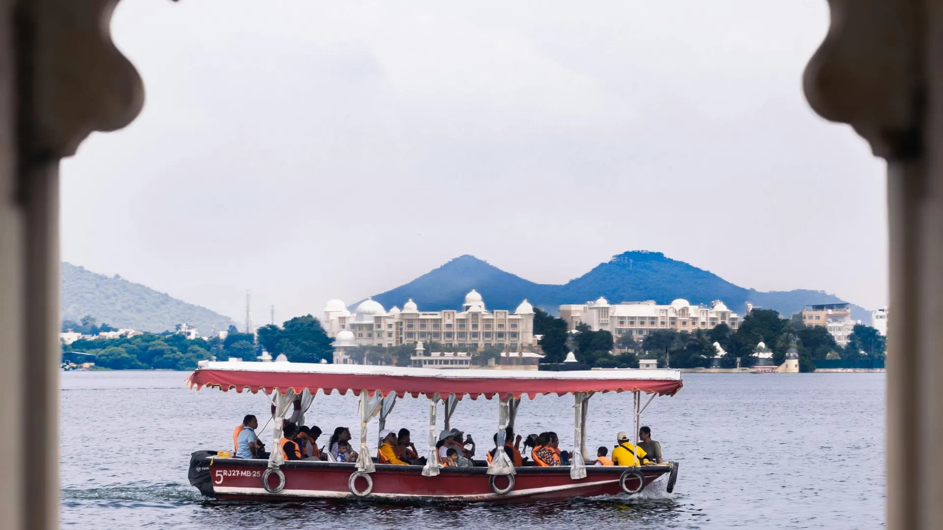 Tourist boat on Lake Pichola framed through palace arches