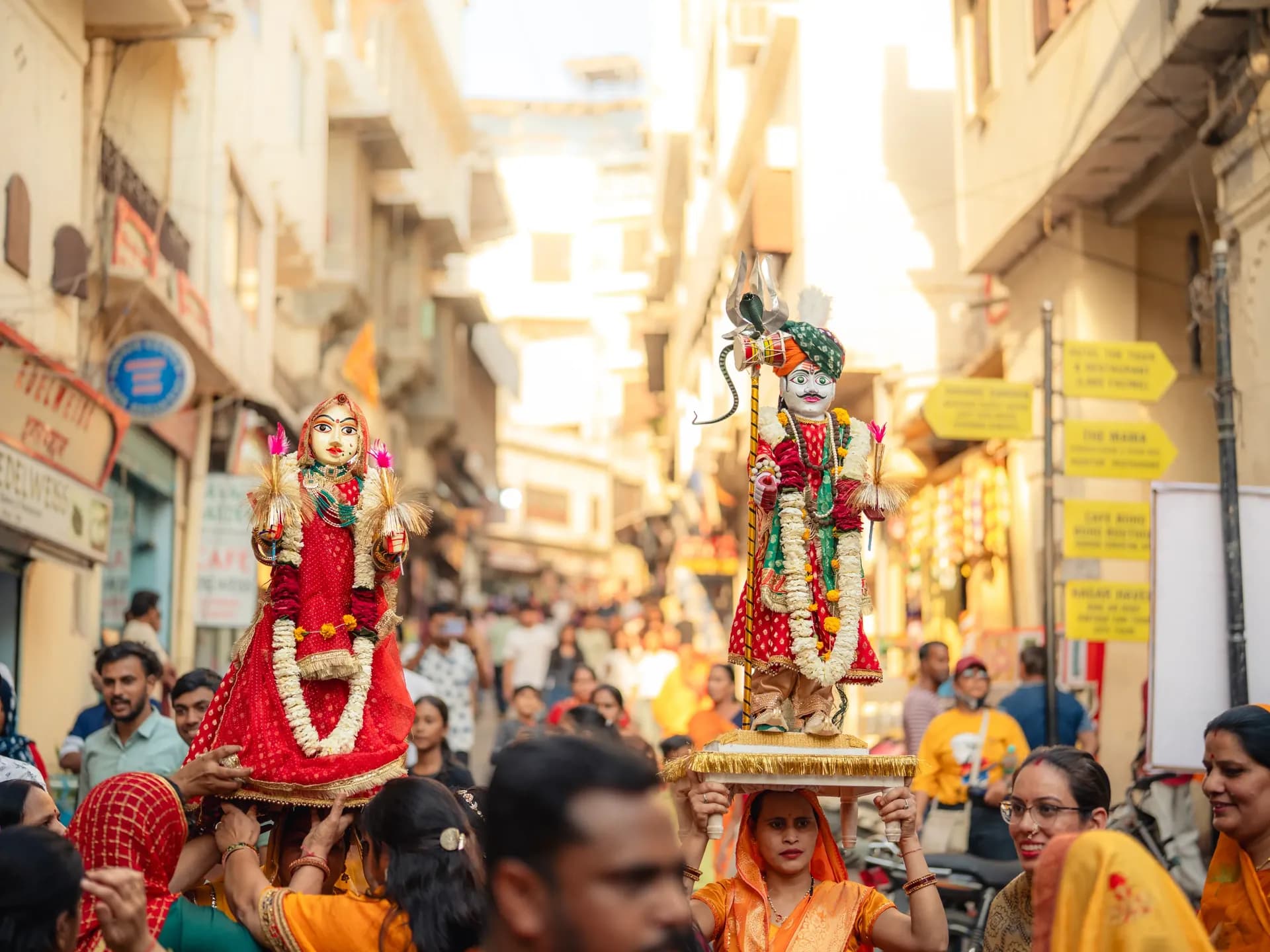 Gangaur idols carried through a crowded old-city lane in Udaipur