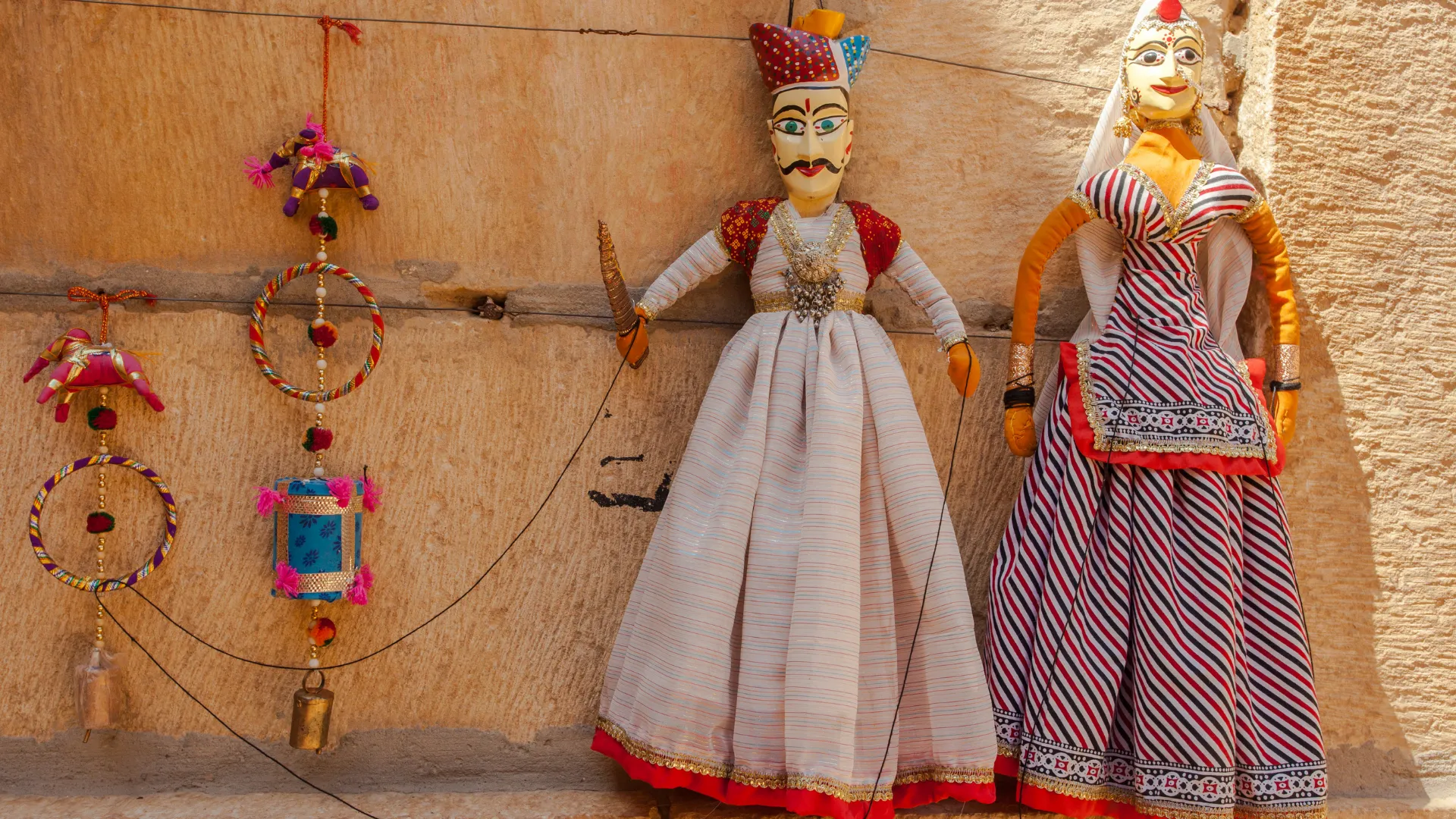 Kathputli puppets and colourful hangings on an ochre wall in an Udaipur shop