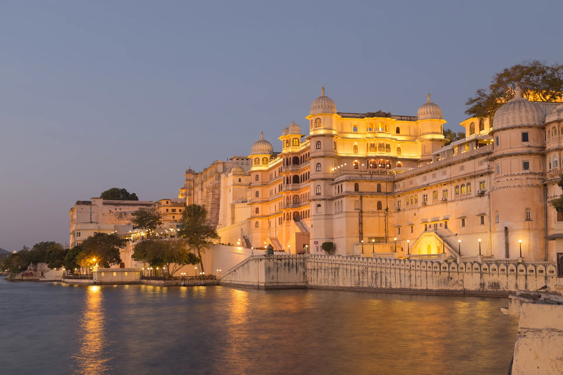City Palace lit up at dusk and reflected in the still water of Lake Pichola