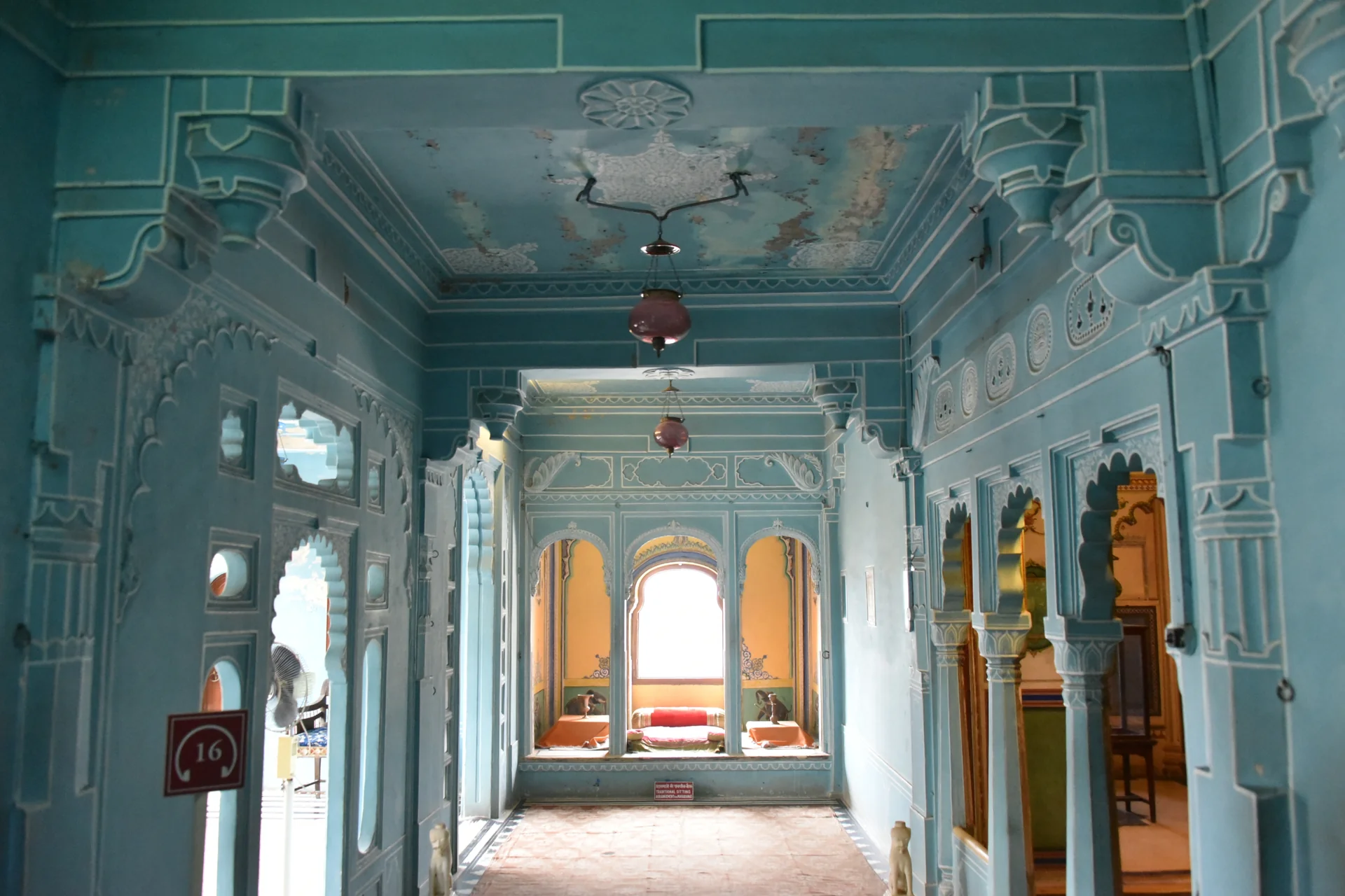 Ornate blue-painted corridor with carved arches inside the City Palace, Udaipur